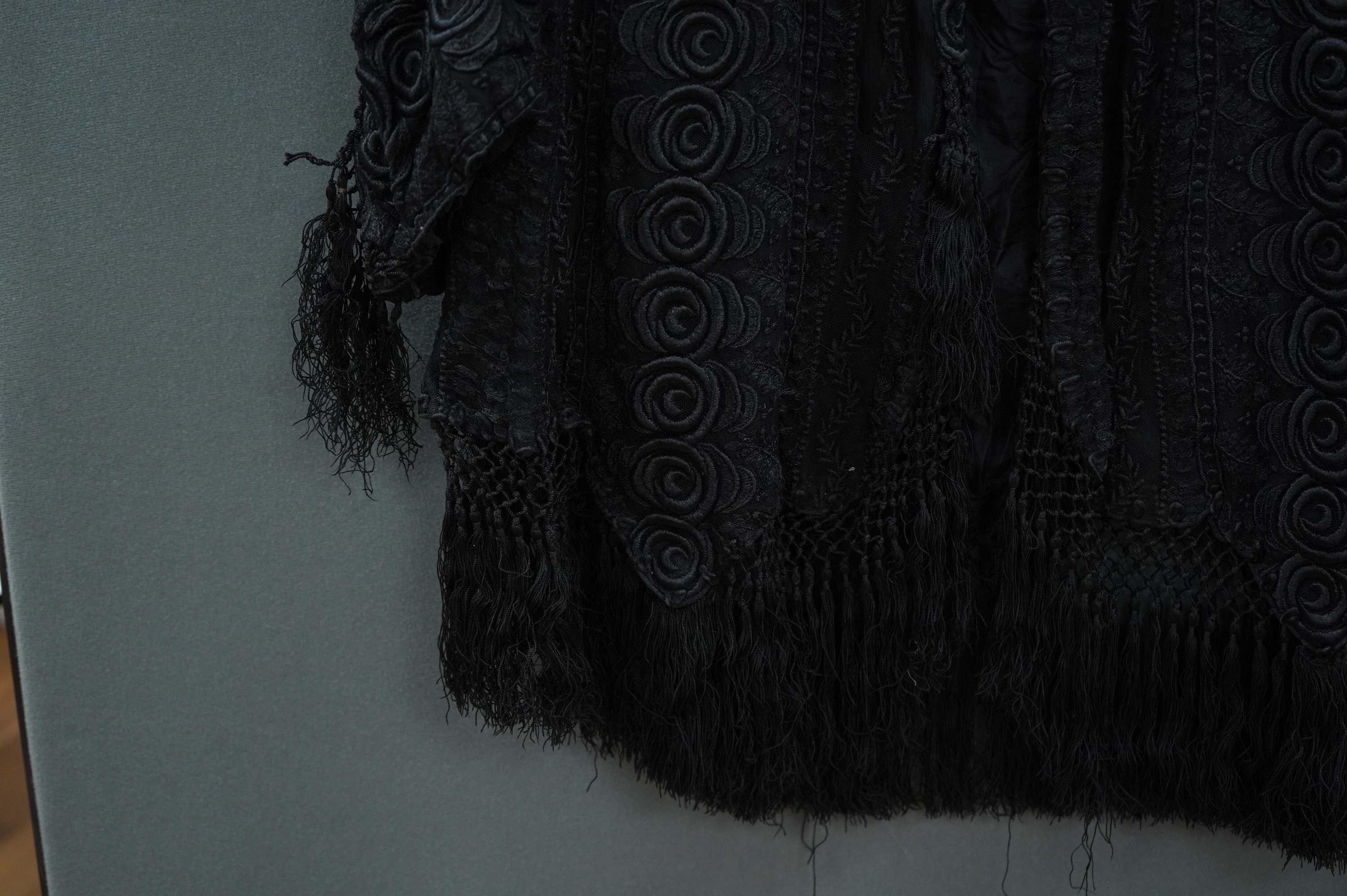 An Edwardian black chiffon and lace evening jacket with tassel decoration to the front and back, edged with tasselled fringing to the edge of sleeves and bottom, 85cm long from nape of neck at the back to bottom of tasse